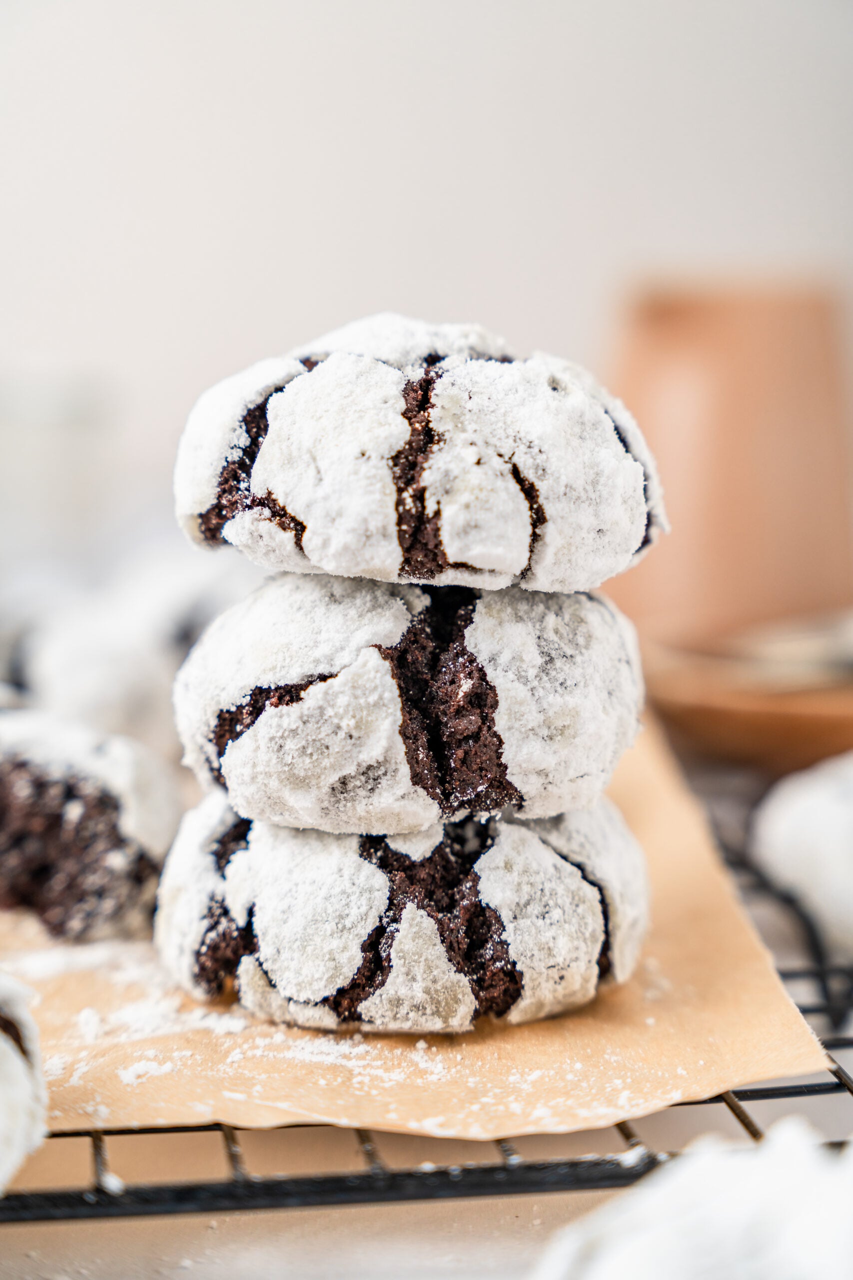 chocolate-crinkle-cookies-stack - Catherine Zhang A stack of three chocolate crinkle cookies on parchment over a wire rack