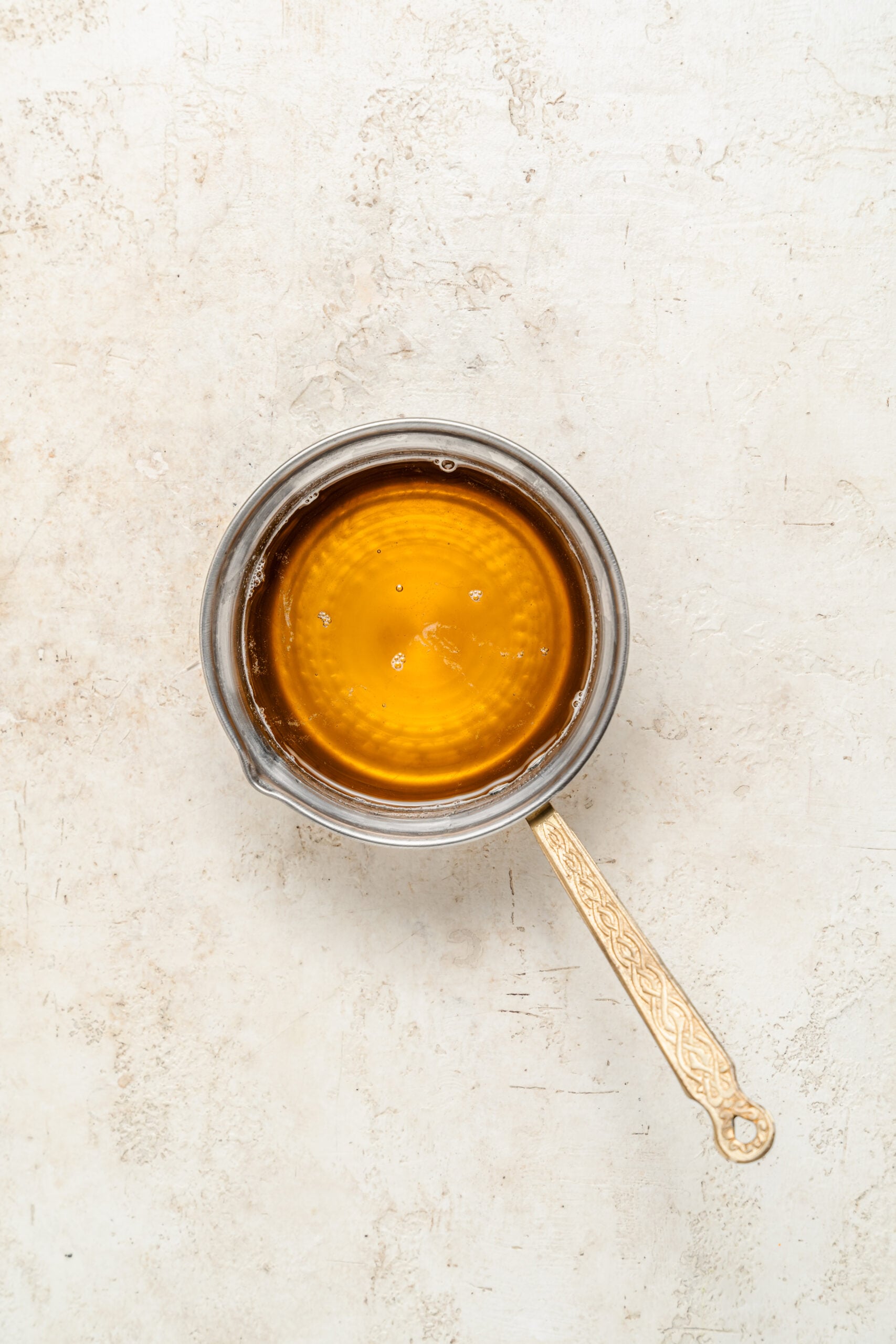 Clarified butter ready for brushing phyllo - Catherine Zhang Clear golden clarified butter poured into a small glass jug with the milk solids left behind