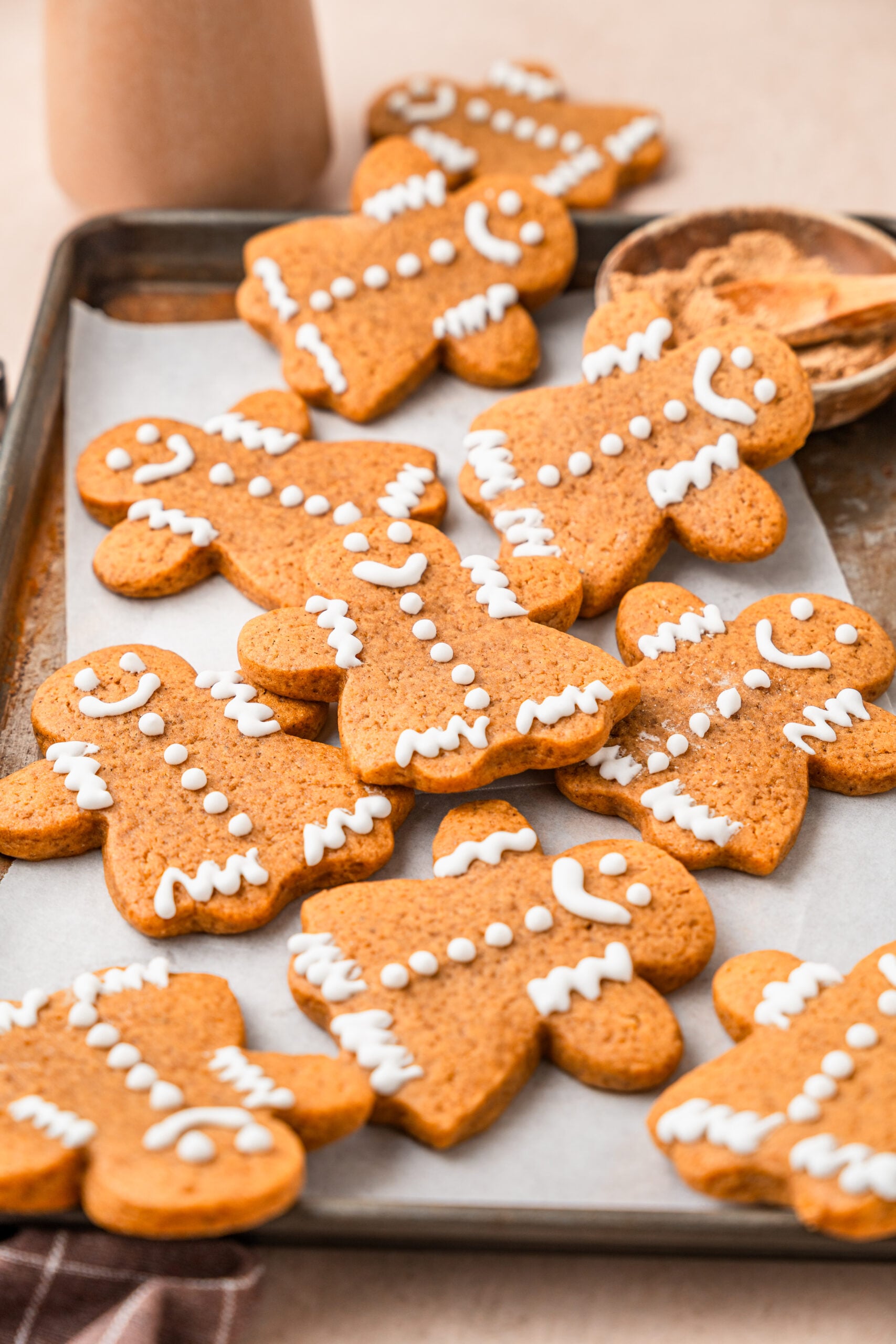 gingerbread-cookies-hero - Catherine Zhang Decorated gingerbread cookies on a lined baking tray with a bowl of ground cinnamon