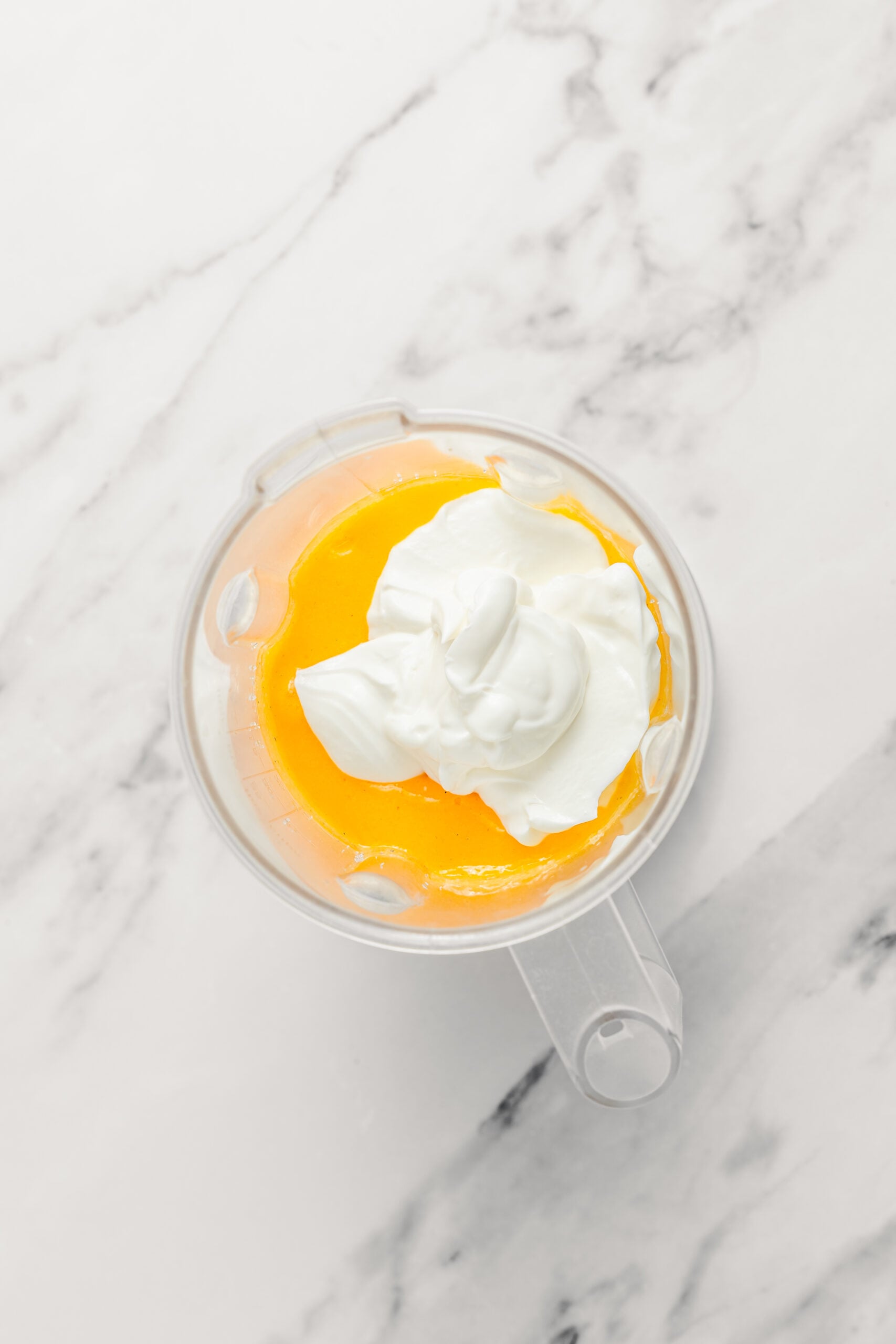 Adding yogurt to the mango puree - Catherine Zhang Plain full fat yogurt spooned on top of the mango puree in the blender jug