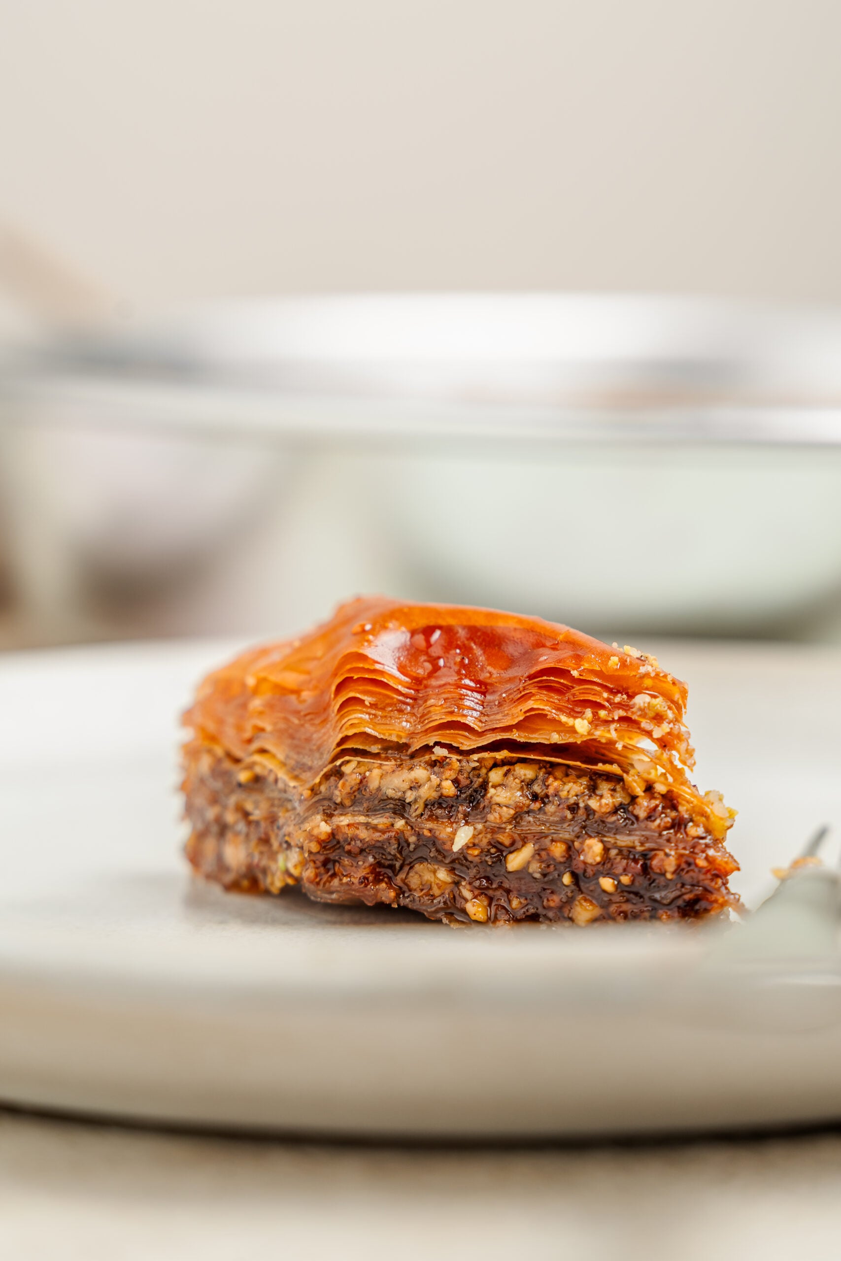 Pistachio baklava cross section - Catherine Zhang A single piece of pistachio baklava on a plate showing the crisp layers and the nut filling in cross section