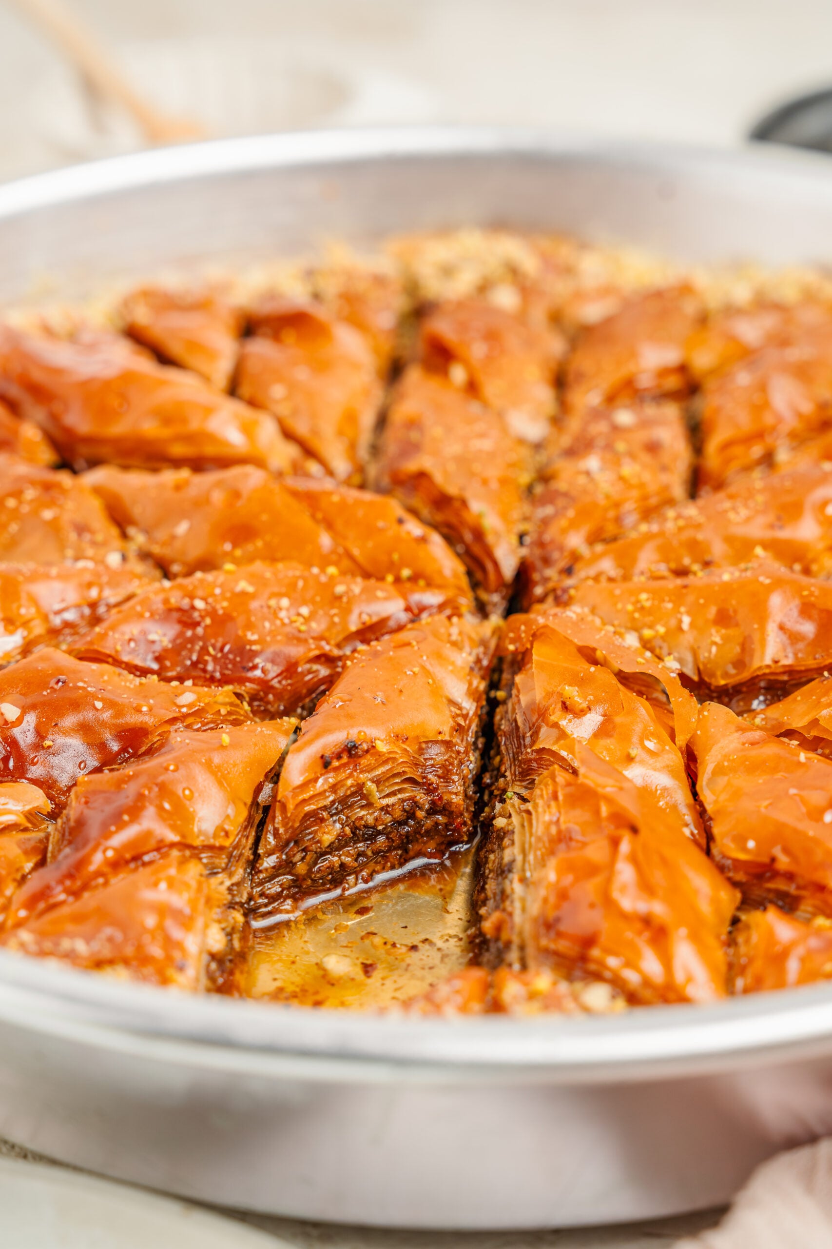 Lifting a piece of pistachio baklava - Catherine Zhang A piece of pistachio baklava lifted away from the tray showing syrup soaked layers