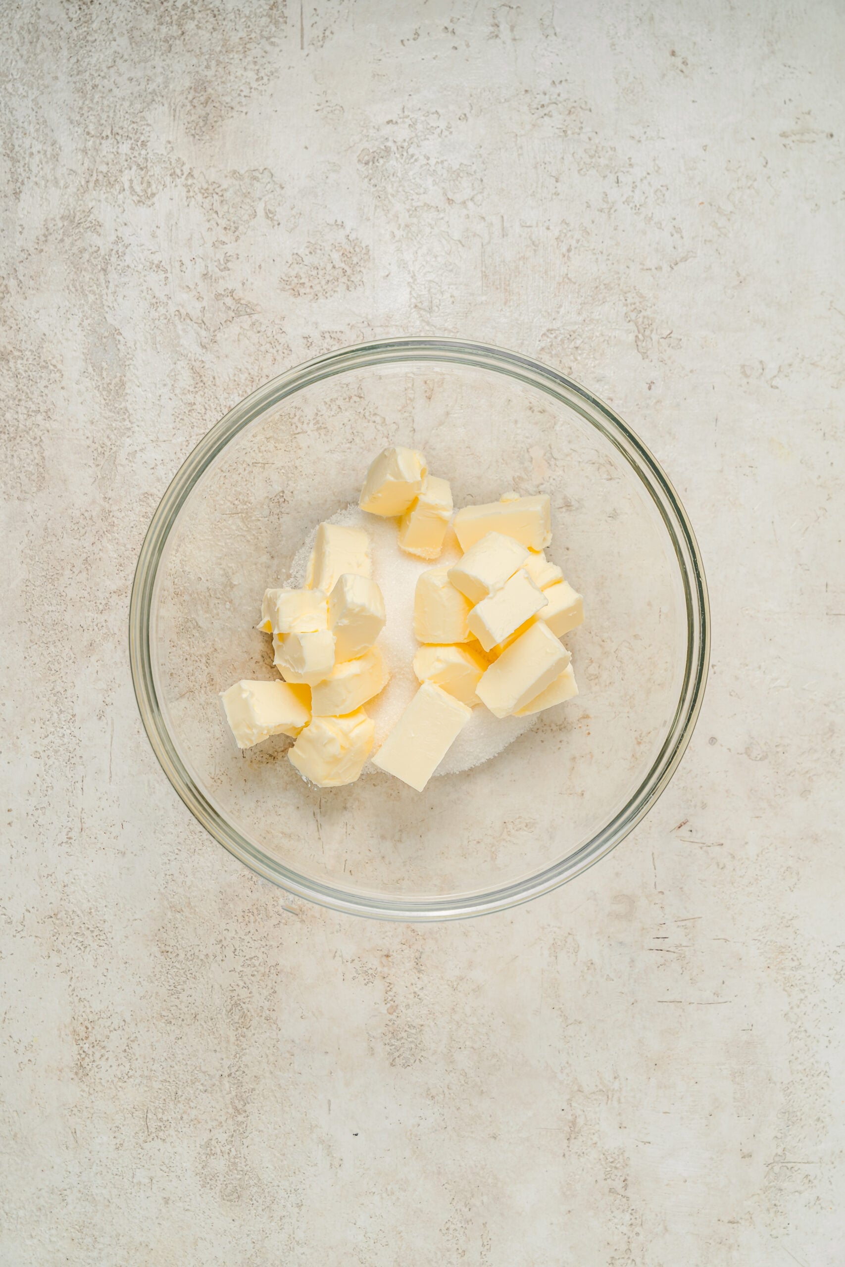 Cubed butter and granulated sugar in a glass mixing bowl - Catherine Zhang Cubed butter and granulated sugar in a glass mixing bowl