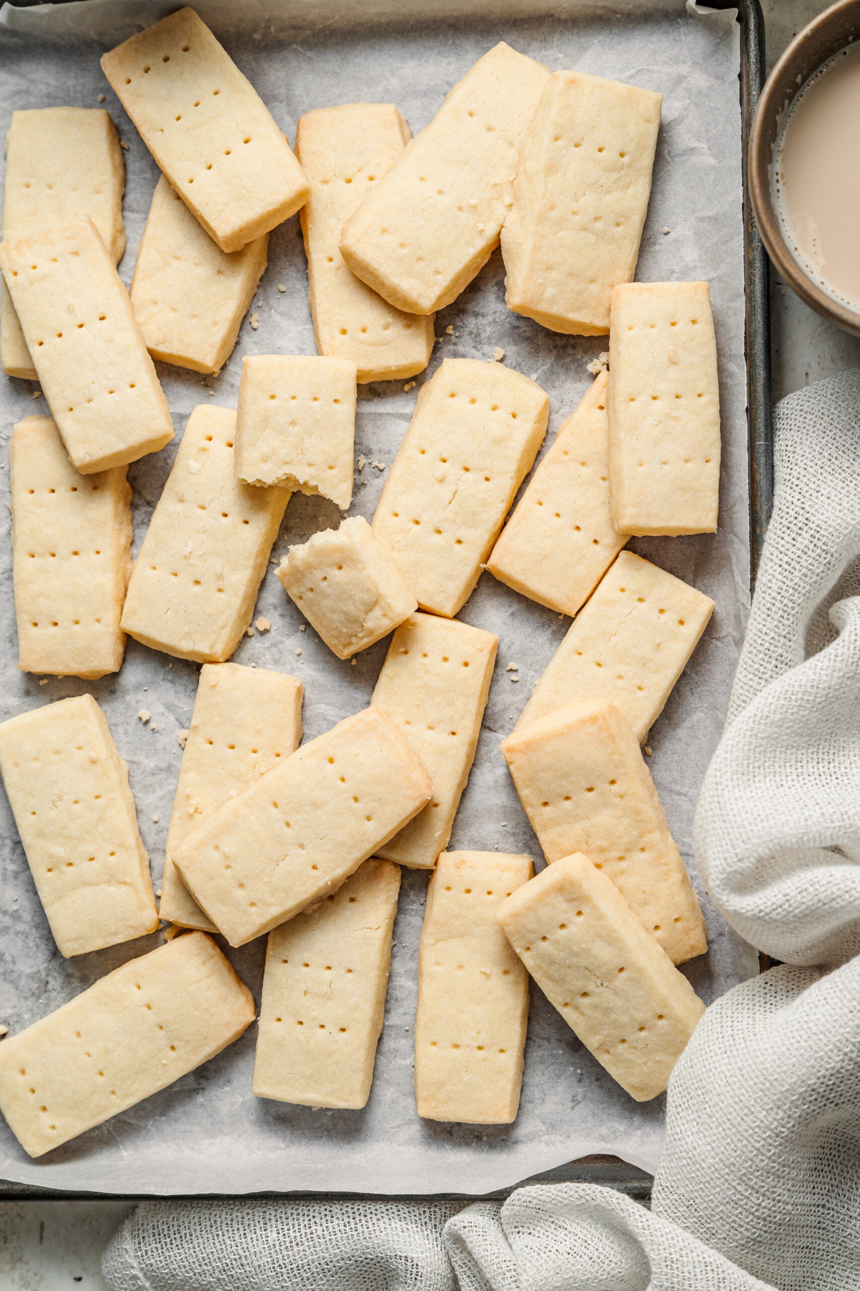 Baked shortbread cookie fingers scattered on a lined baking tray - Catherine Zhang Baked shortbread cookie fingers scattered on a lined baking tray