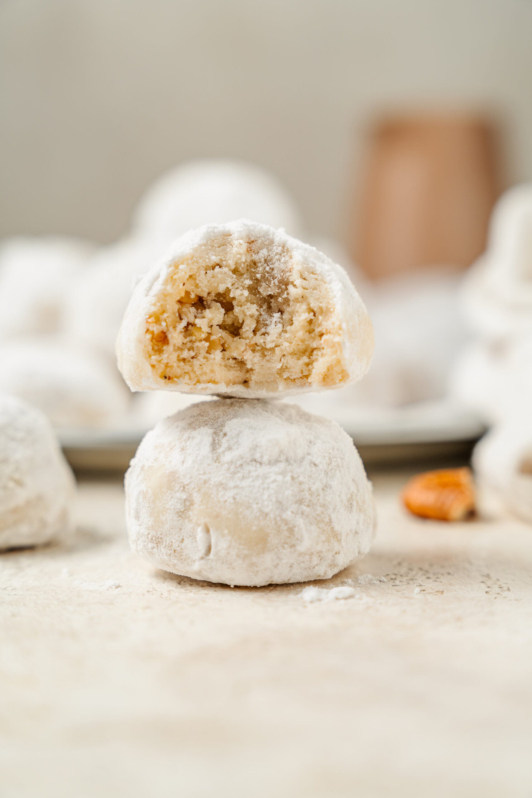 Two snowball cookies stacked, the top one bitten to show the pecan crumb - Catherine Zhang Two snowball cookies stacked, the top one bitten to show the pecan crumb