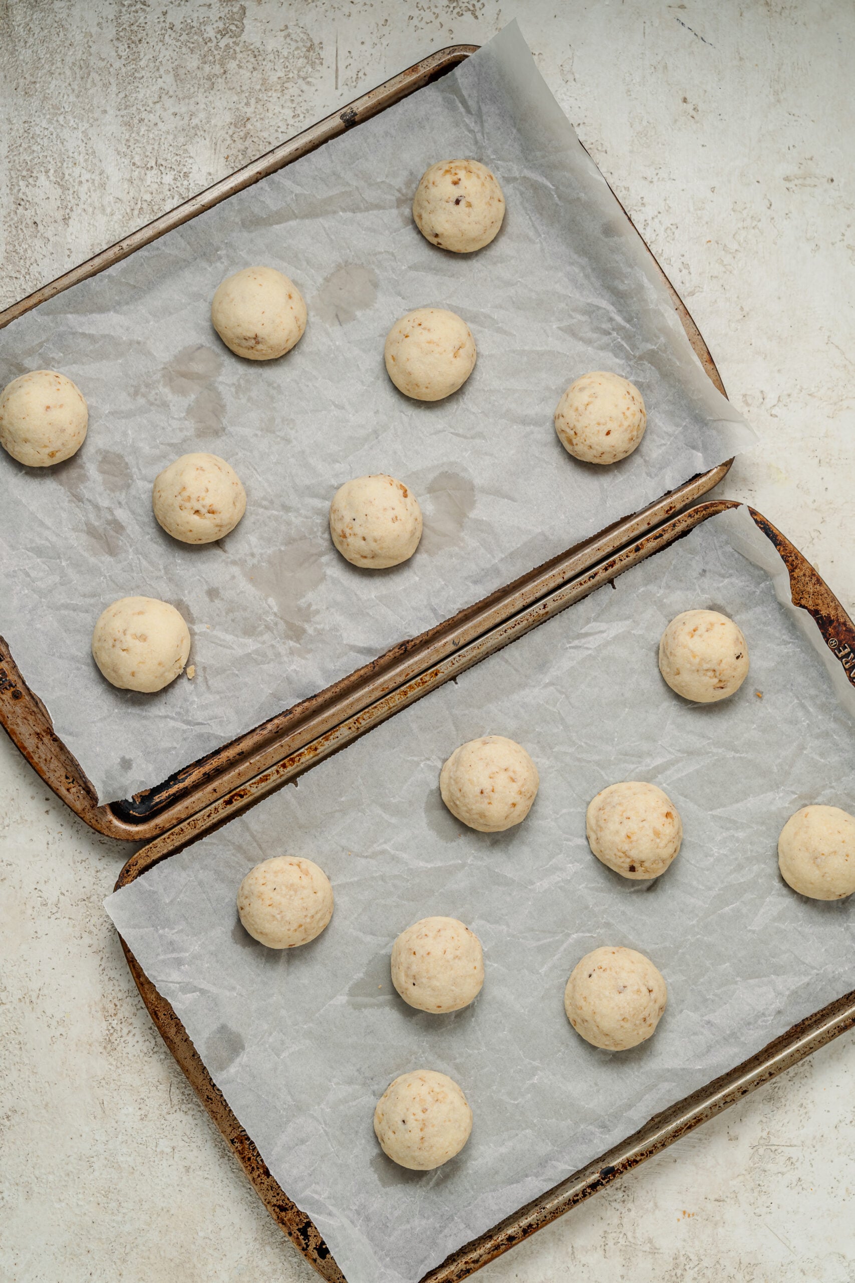 Two trays of rolled snowball cookie dough balls ready to chill - Catherine Zhang Two trays of rolled snowball cookie dough balls ready to chill