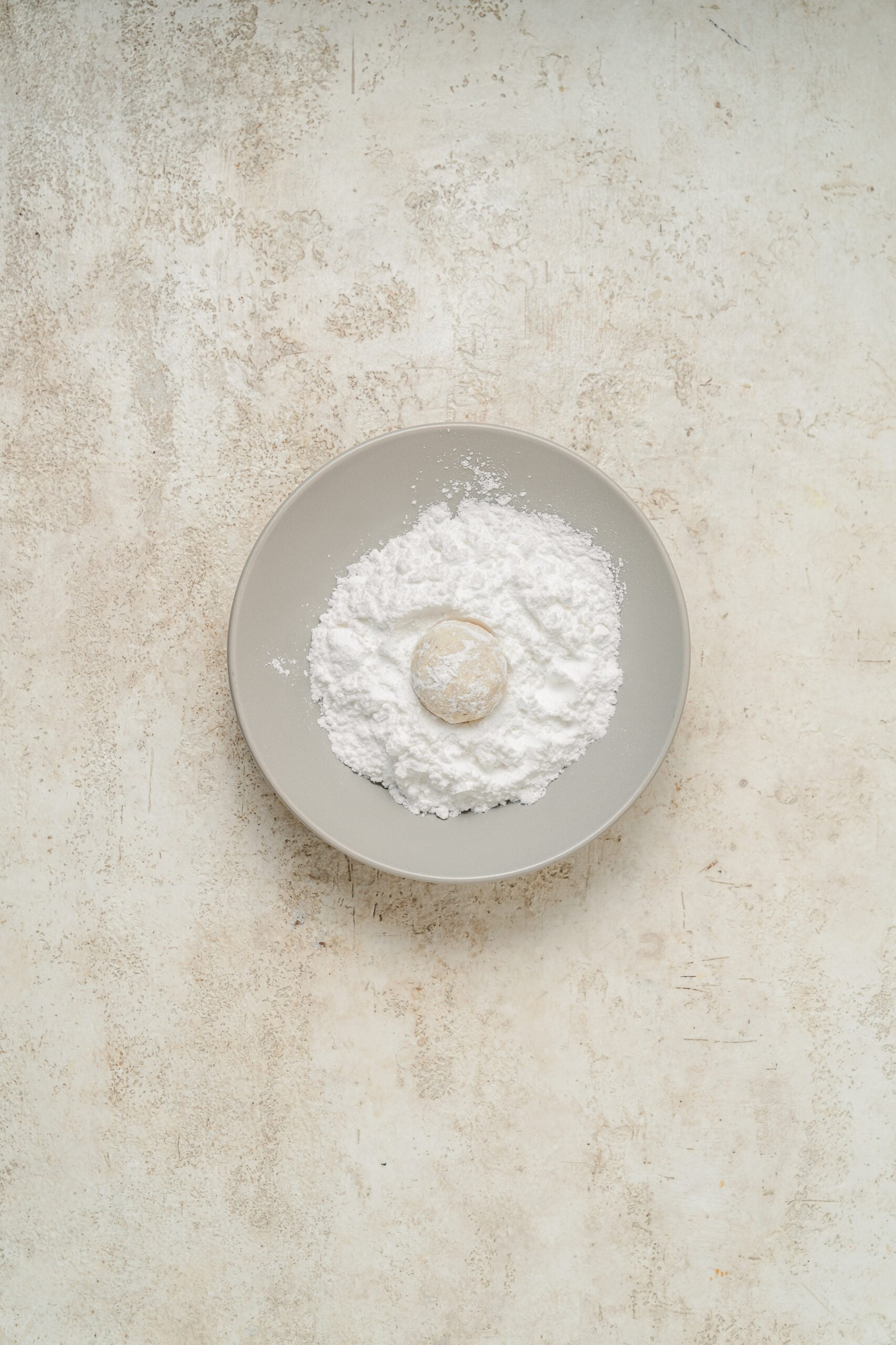 A snowball cookie coated in its first layer of powdered sugar - Catherine Zhang A snowball cookie coated in its first layer of powdered sugar