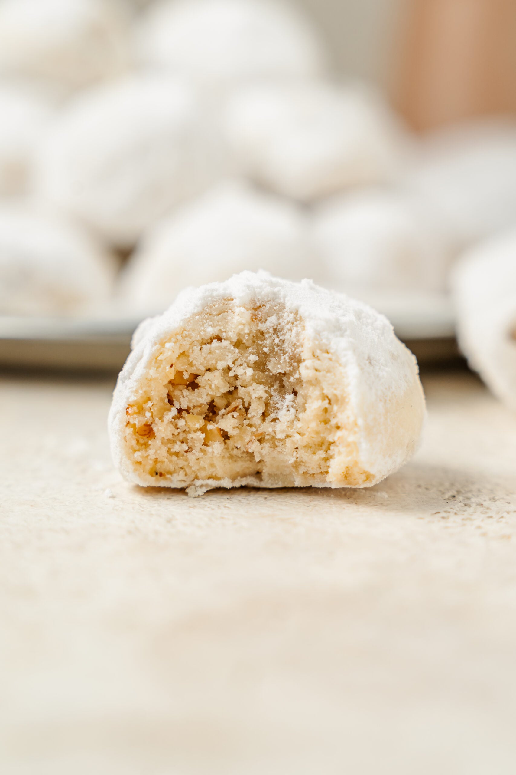 A snowball cookie bitten open to show the finely chopped pecans inside - Catherine Zhang A snowball cookie bitten open to show the finely chopped pecans inside