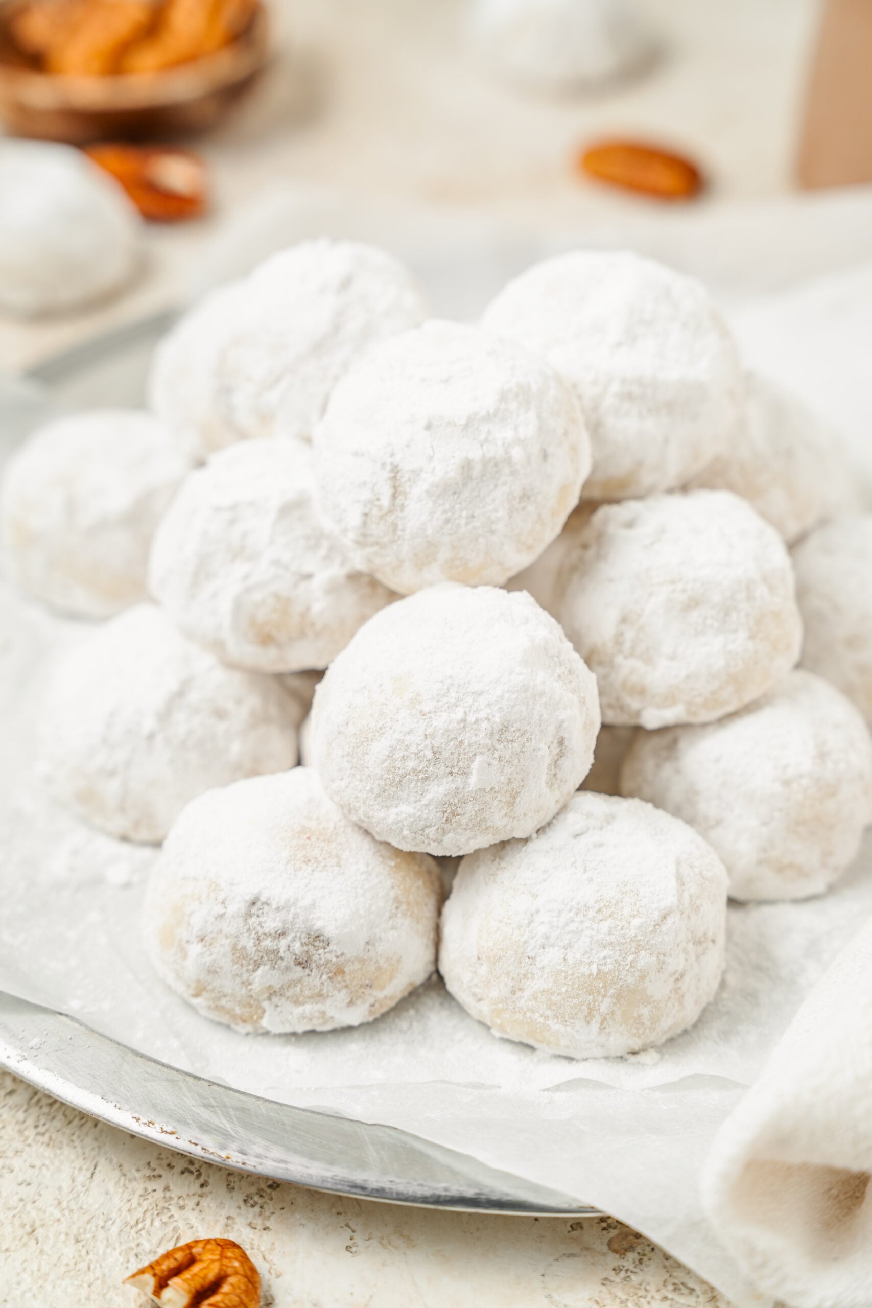Snowball cookies stacked on a plate in a drift of powdered sugar - Catherine Zhang Snowball cookies stacked on a plate in a drift of powdered sugar