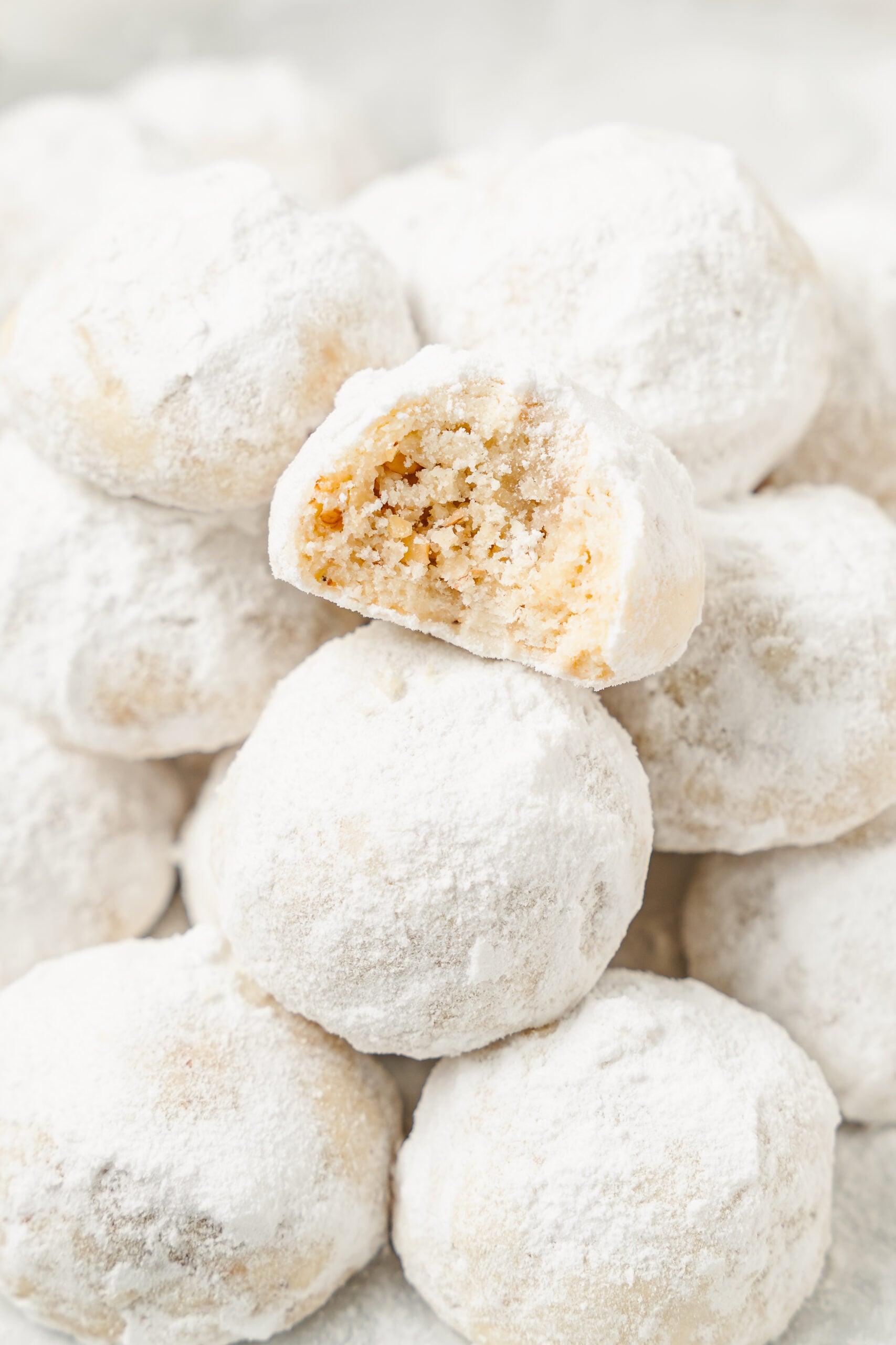 A snowball cookie bitten open resting on a pile of sugar coated cookies - Catherine Zhang A snowball cookie bitten open resting on a pile of sugar coated cookies