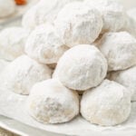 A plate piled with snowball cookies coated in powdered sugar
