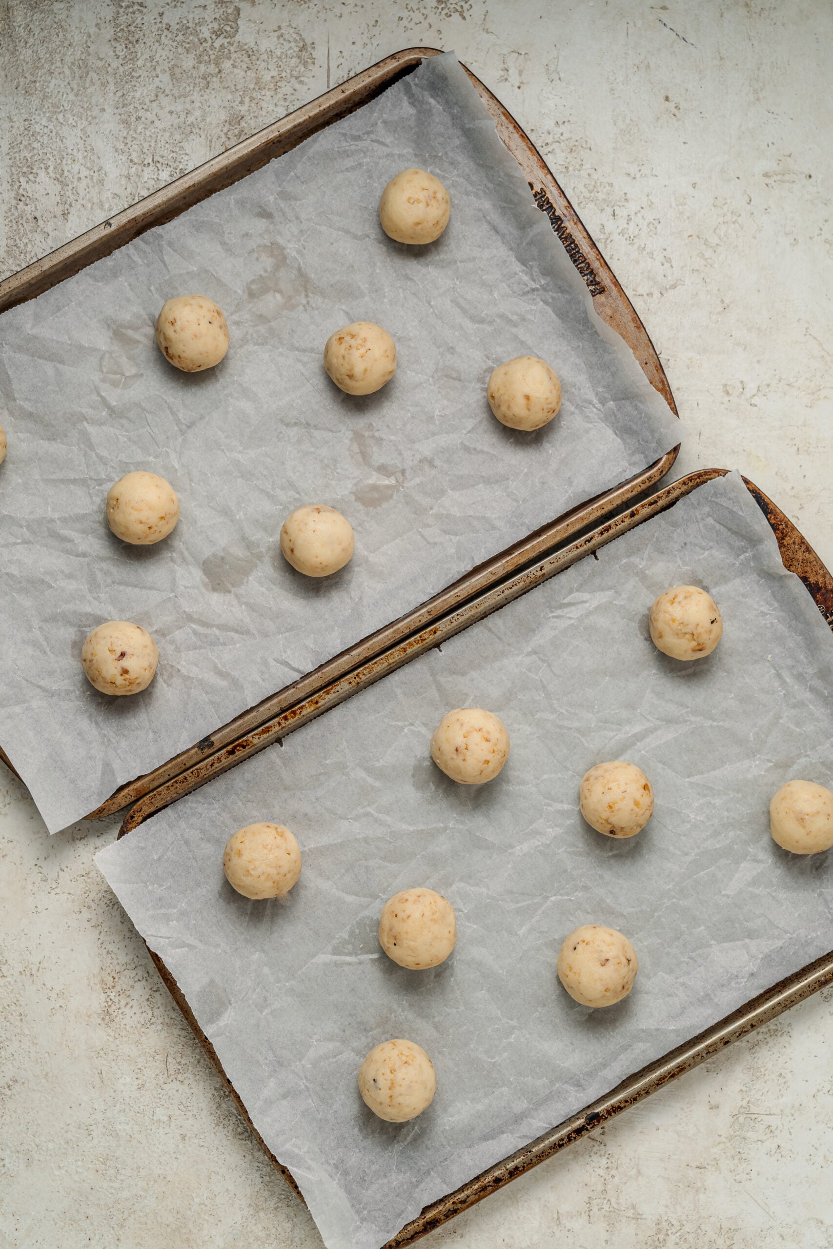 Snowball cookie dough rolled into balls and spaced on lined trays - Catherine Zhang Snowball cookie dough rolled into balls and spaced on lined trays