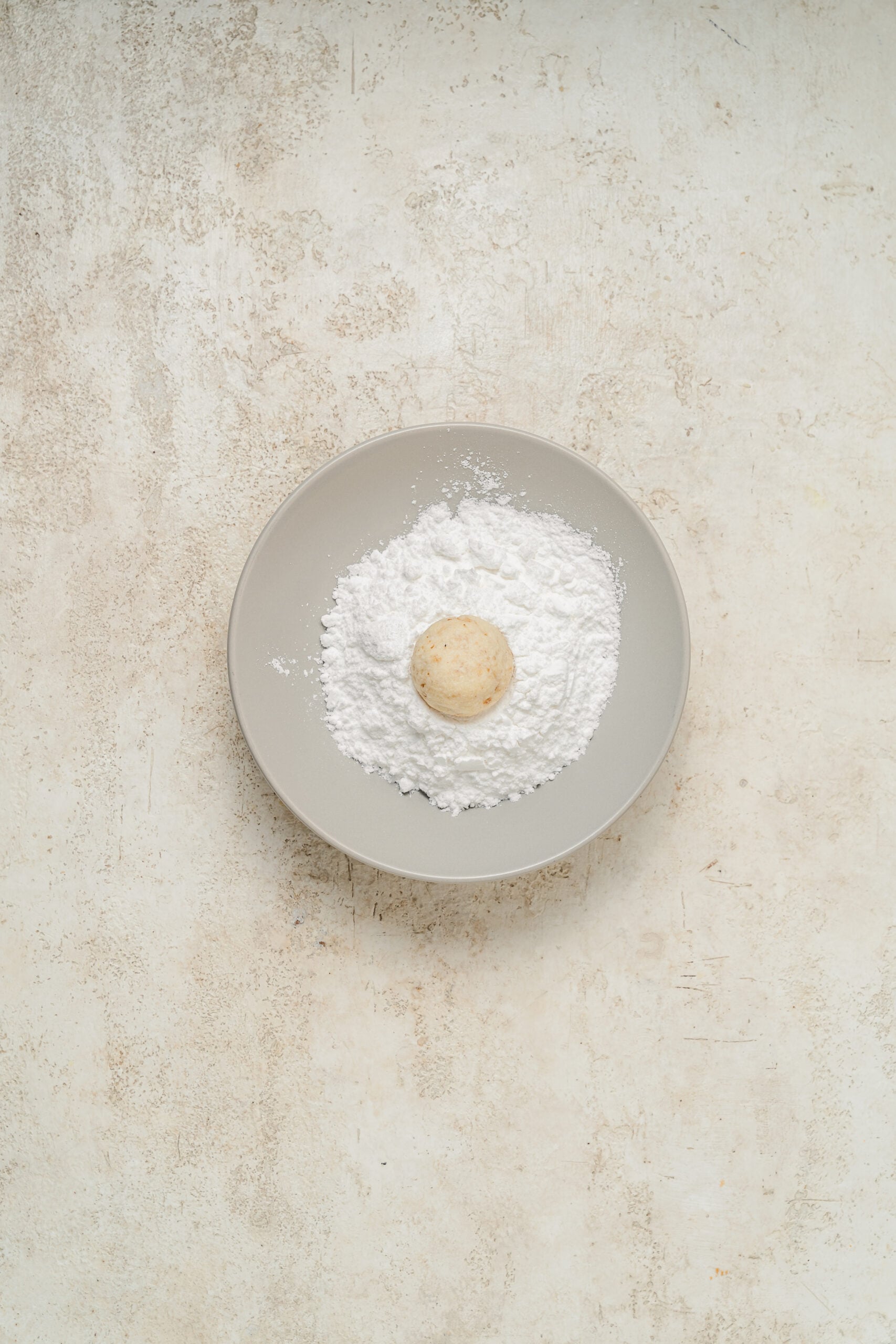 A warm snowball cookie being rolled in a bowl of powdered sugar - Catherine Zhang A warm snowball cookie being rolled in a bowl of powdered sugar