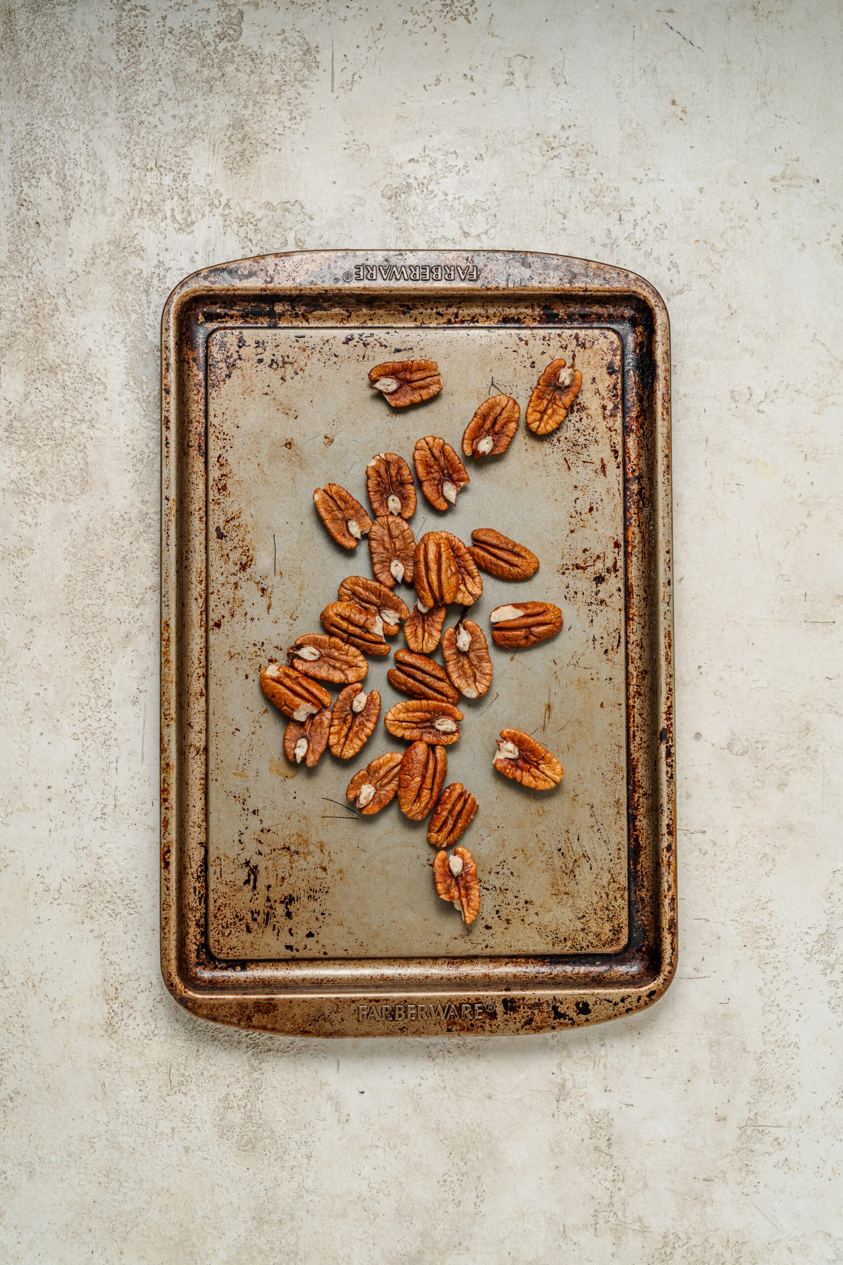 Pecan halves spread on a baking tray ready to toast - Catherine Zhang Pecan halves spread on a baking tray ready to toast
